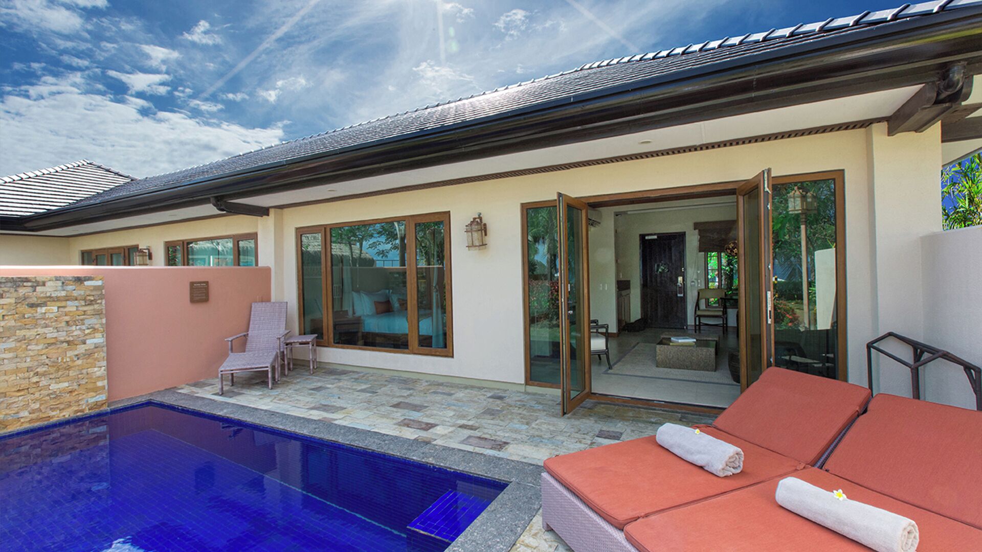 A modern house with a swimming pool, glass doors, and a patio area.
