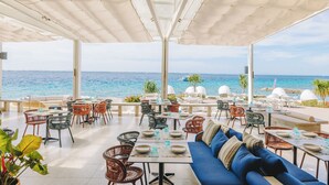 An outdoor seating area with tables and chairs, overlooking the sea. - Crimson Resort and Spa Mactan (Lapu-Lapu)