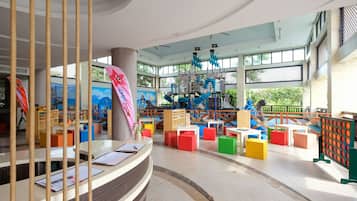 Children can play and socialize in this vibrant indoor play area featuring a climbing structure, slides, and open play spaces.