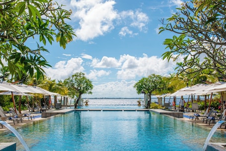 Una piscina al aire libre, sombrillas, sillones reclinables de piscina