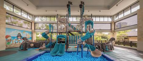 A children's play area with slides and climbing structures surrounded by blue balls.