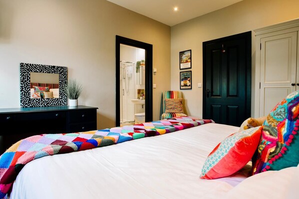 A bedroom with a large bed, a dresser, a mirror, and a door.