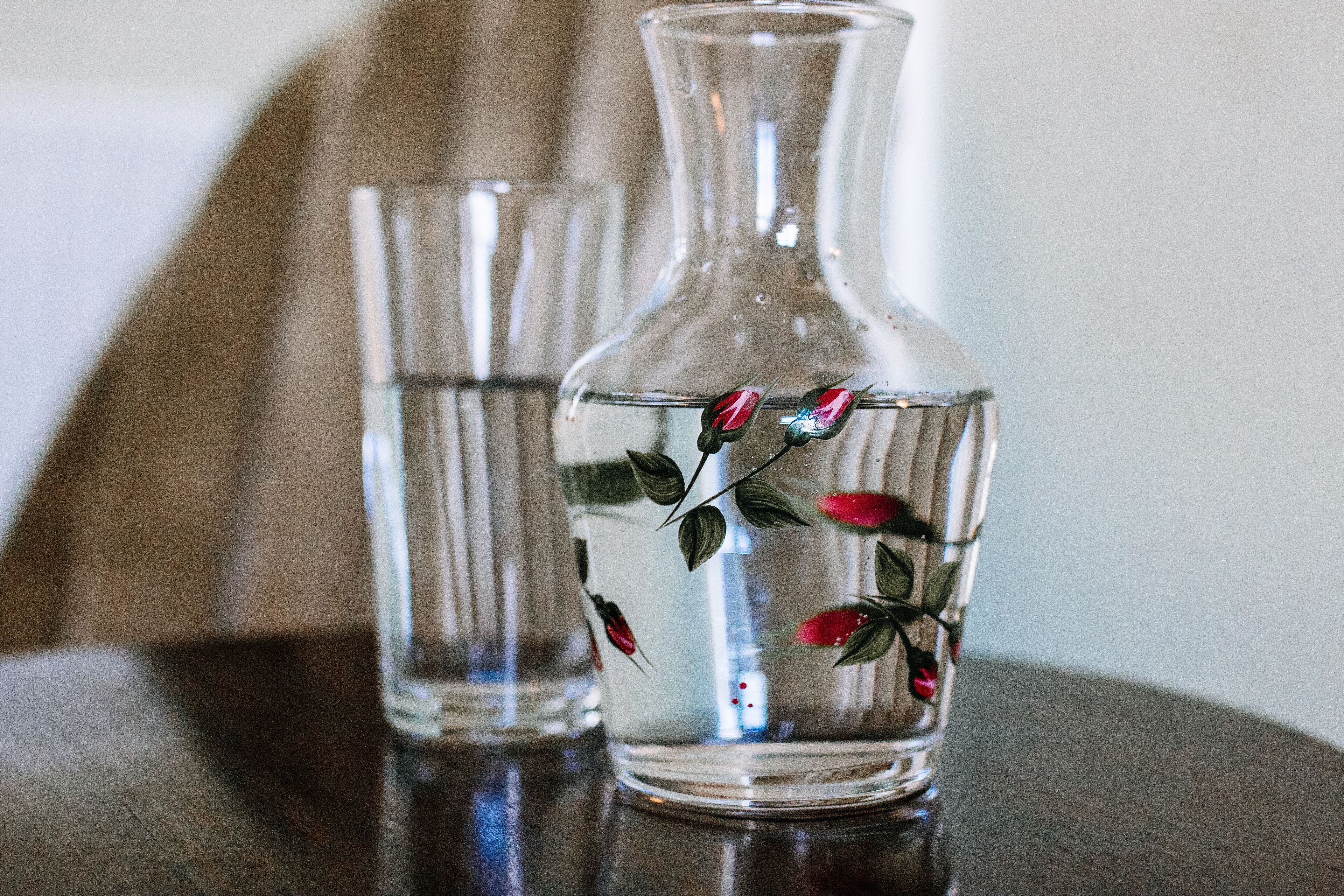 Two clear glass vases with floral designs on a wooden surface.