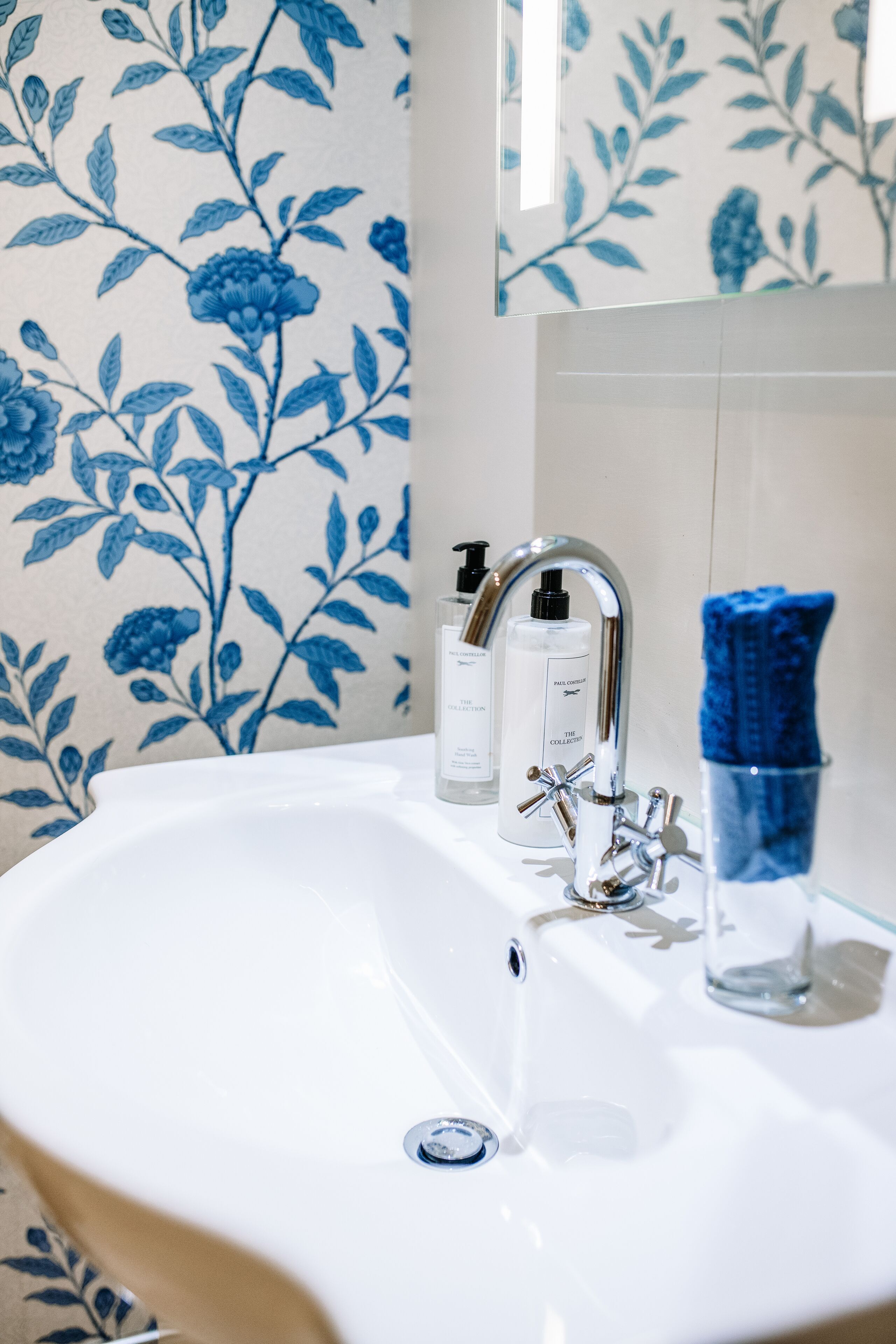 A bathroom with a white sink, a chrome faucet, and a blue towel.