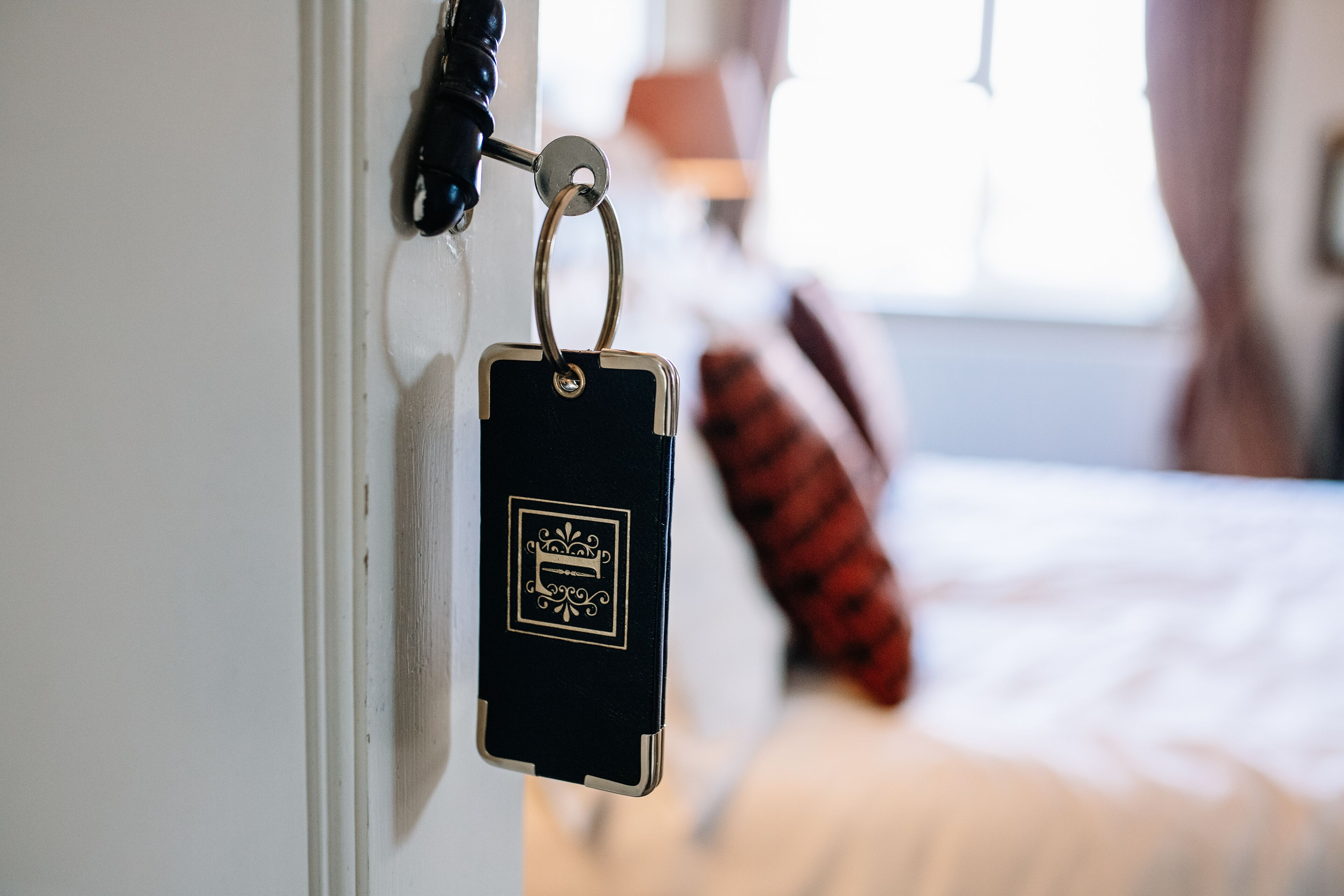 A key hanging on a door with a bed in the background.