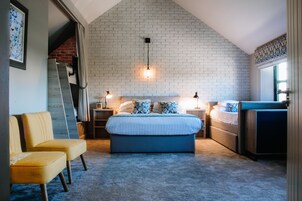 Um quarto com teto inclinado, uma cama grande, duas mesas de cabeceira, uma cadeira e um guarda-roupa.