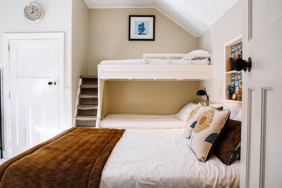 A bedroom with bunk beds, a staircase, a clock, and a framed picture on the wall.