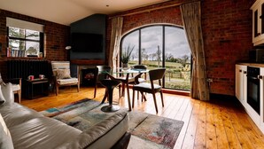 Una sala de estar acogedora con chimenea, un comedor y un amplio ventanal con vistas al campo.