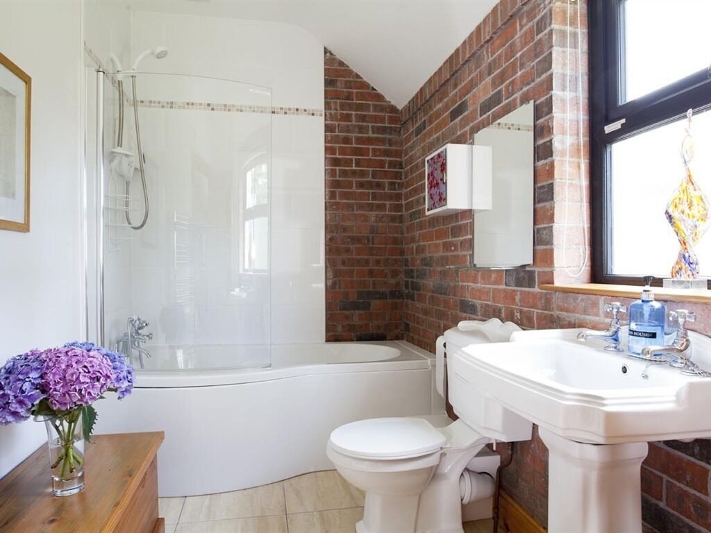 A bathroom with a glass-enclosed shower, a white toilet, and a sink with a mirror above it.