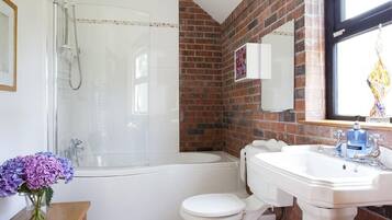 A bathroom with a glass-enclosed shower, a white toilet, and a sink with a mirror above it.