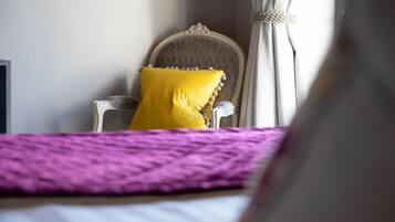 Una cama con un edredón morado, una almohada amarilla y un cabecero blanco.