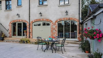 Un edificio con fachada de ladrillo, ventanas arqueadas y un patio con mesa y sillas.