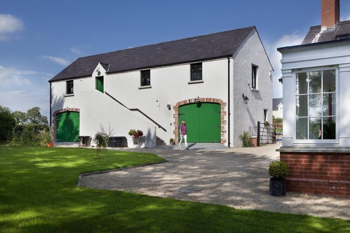 A two-story house with a green door, a brick chimney, and a small garden.