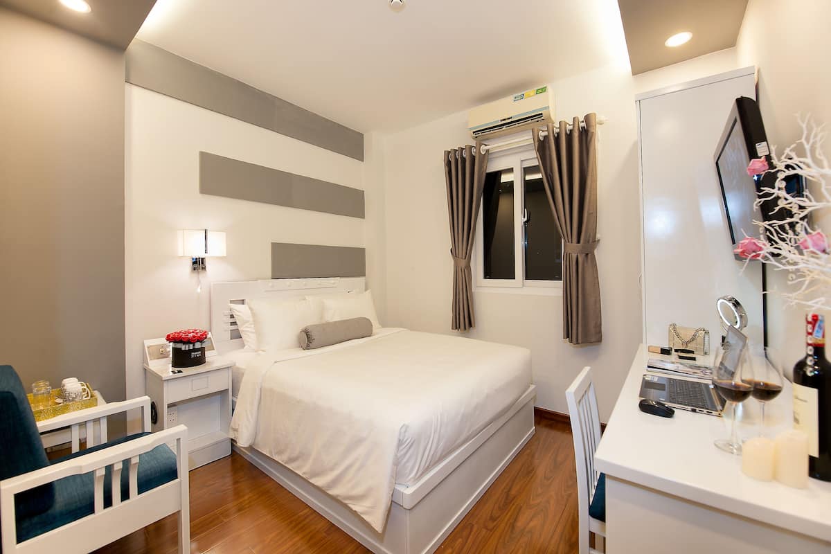 Une chambre d’hôtel moderne équipée d’un lit, d’une table de chevet, d’un bureau et d’un miroir.