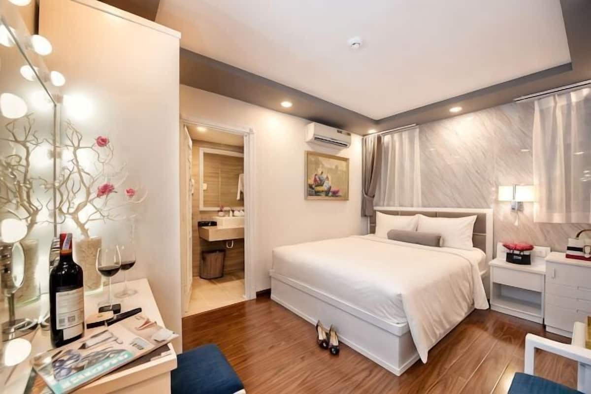 Une chambre d’hôtel moderne avec un grand lit, une table de chevet et une coiffeuse avec un miroir.