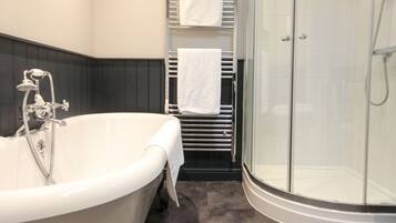 A modern bathroom with a freestanding bathtub, a glass-enclosed shower, and a towel rack with white towels.