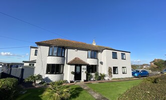 A two-story house with a tiled roof, a front entrance, and a small garden.