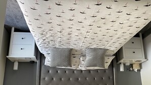A neatly made bed with a patterned bedspread, two bedside tables with lamps, and a tufted headboard. - Waterside Guest House (Romney Marsh)
