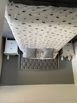 A neatly made bed with a patterned bedspread, two bedside tables with lamps, and a tufted headboard.