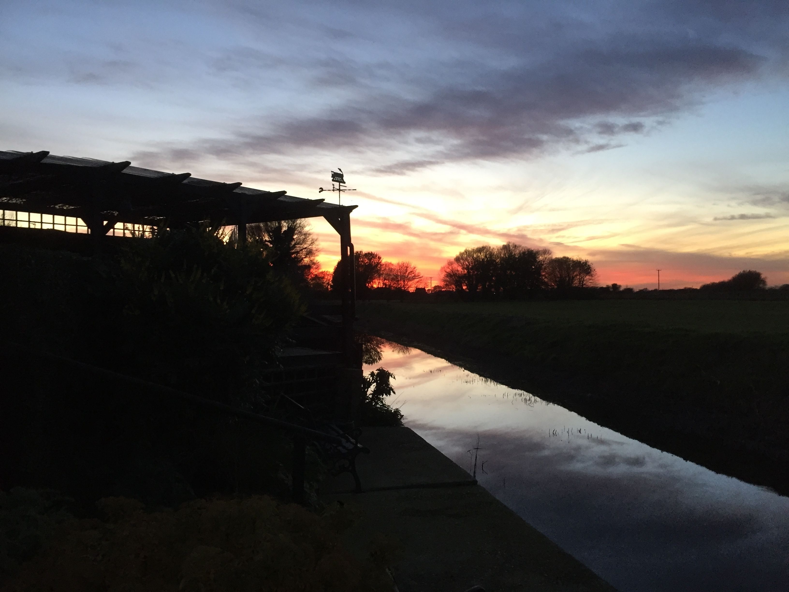 A sunset over a calm river with a building on the left.
