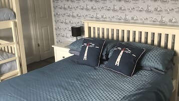 A bedroom with a bed, a nightstand, a lamp, and a wardrobe.
