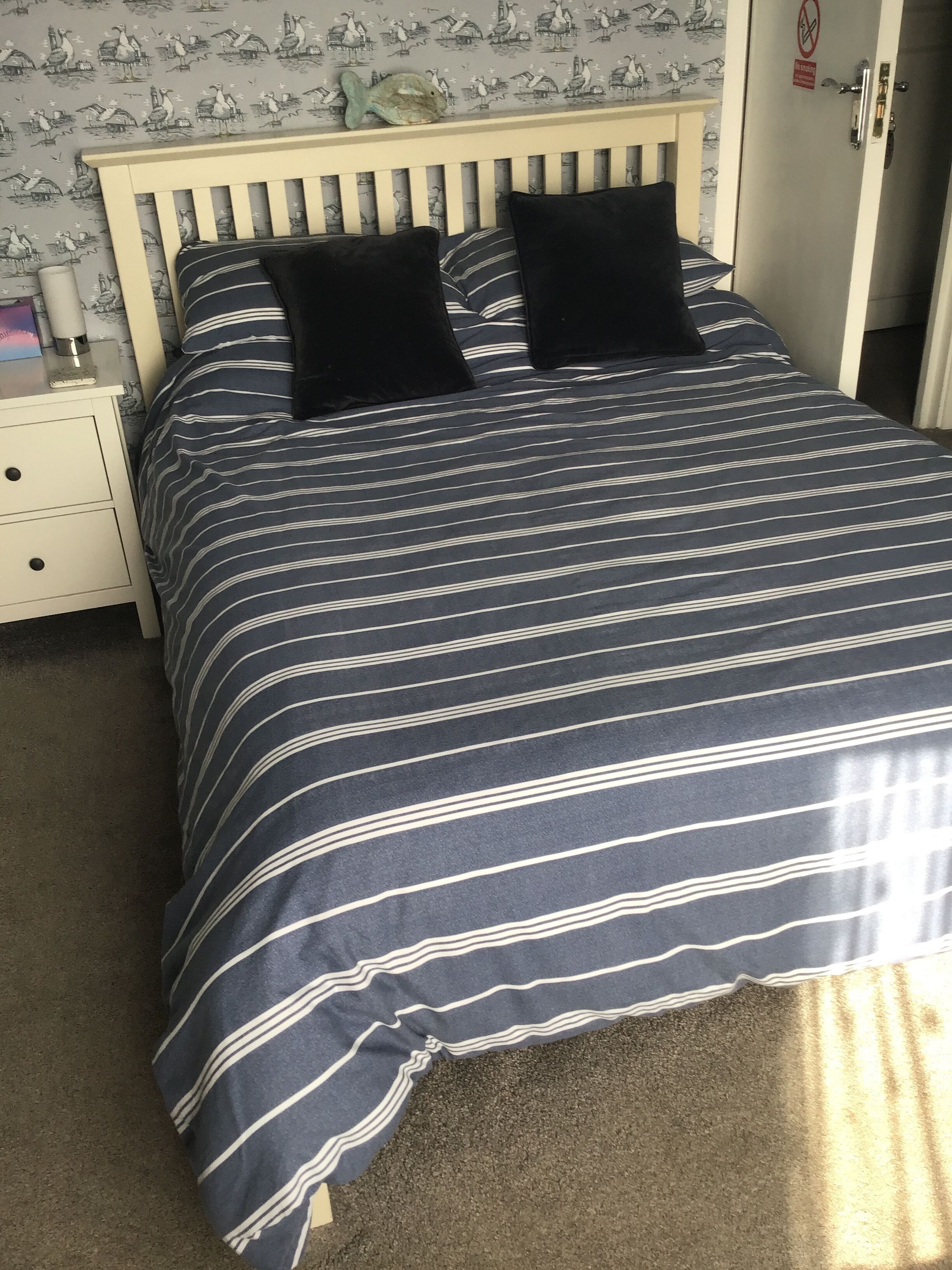 A bed with a striped bedspread, two black pillows, and a wooden headboard.