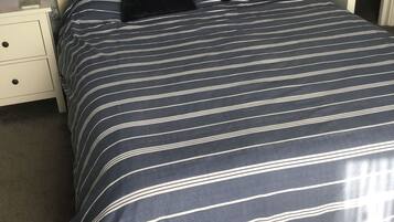 A bed with a striped bedspread, two black pillows, and a wooden headboard.