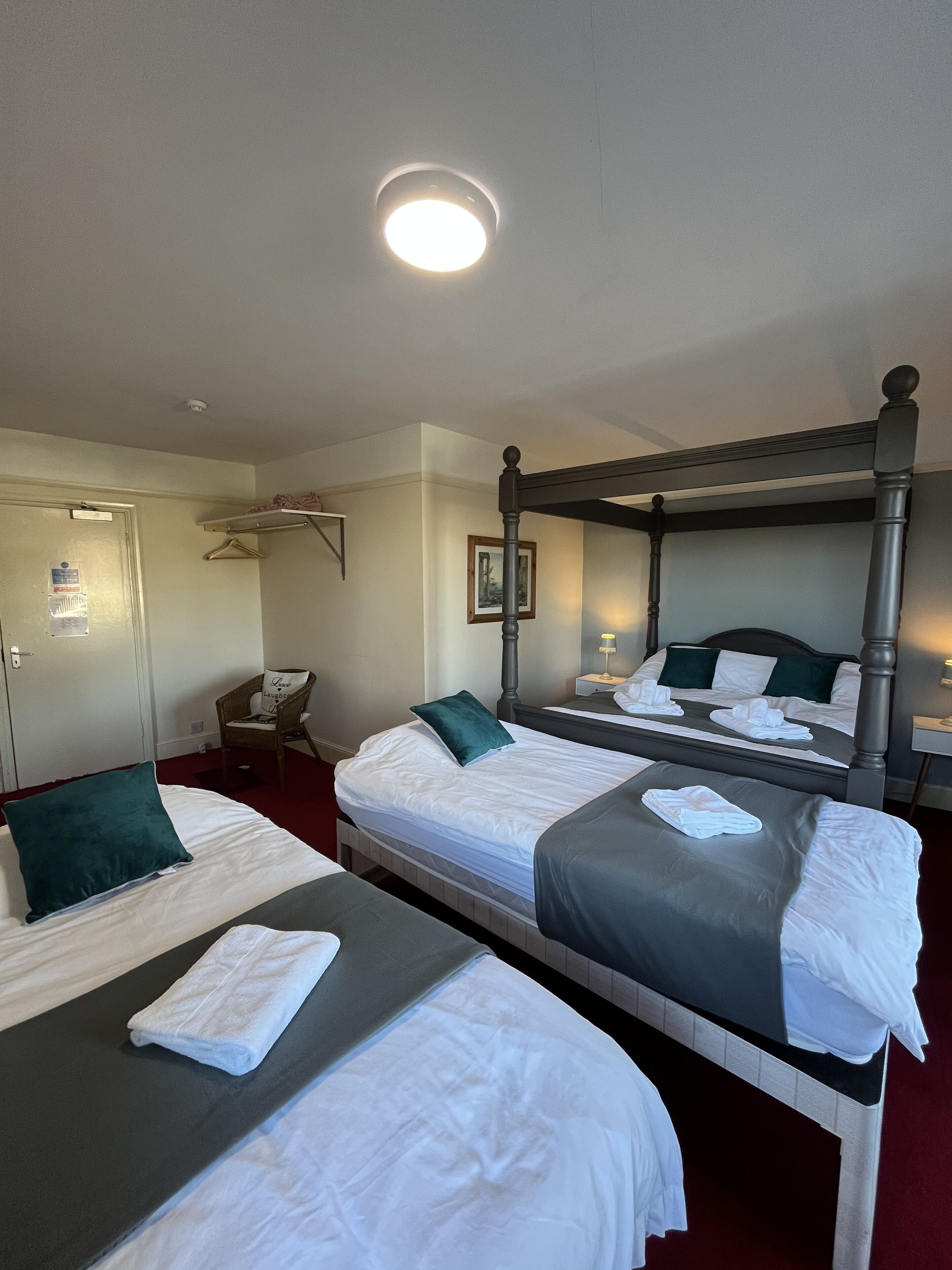 A hotel room with two beds, a chair, a desk, and a mirror.