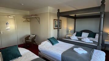 A hotel room with two beds, a chair, a desk, and a mirror.