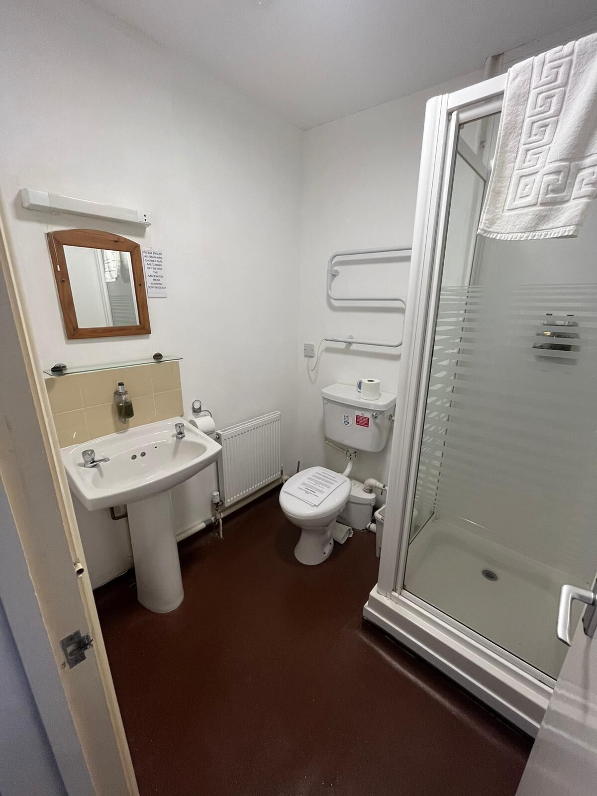 A small, clean bathroom with a sink, toilet, and glass shower enclosure.