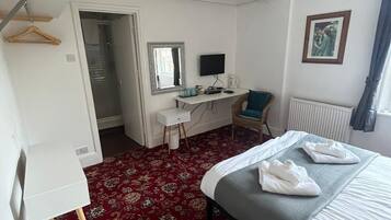 Une chambre d’hôtel équipée d’un lit, d’un bureau, d’une armoire et d’un radiateur.