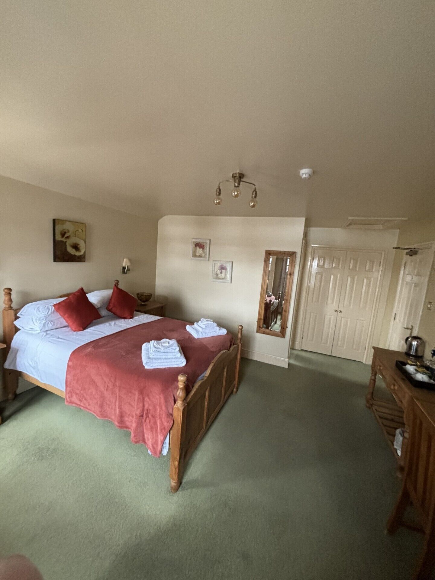 Une chambre à coucher comprenant un lit, une table de chevet, une commode, un miroir et une porte.