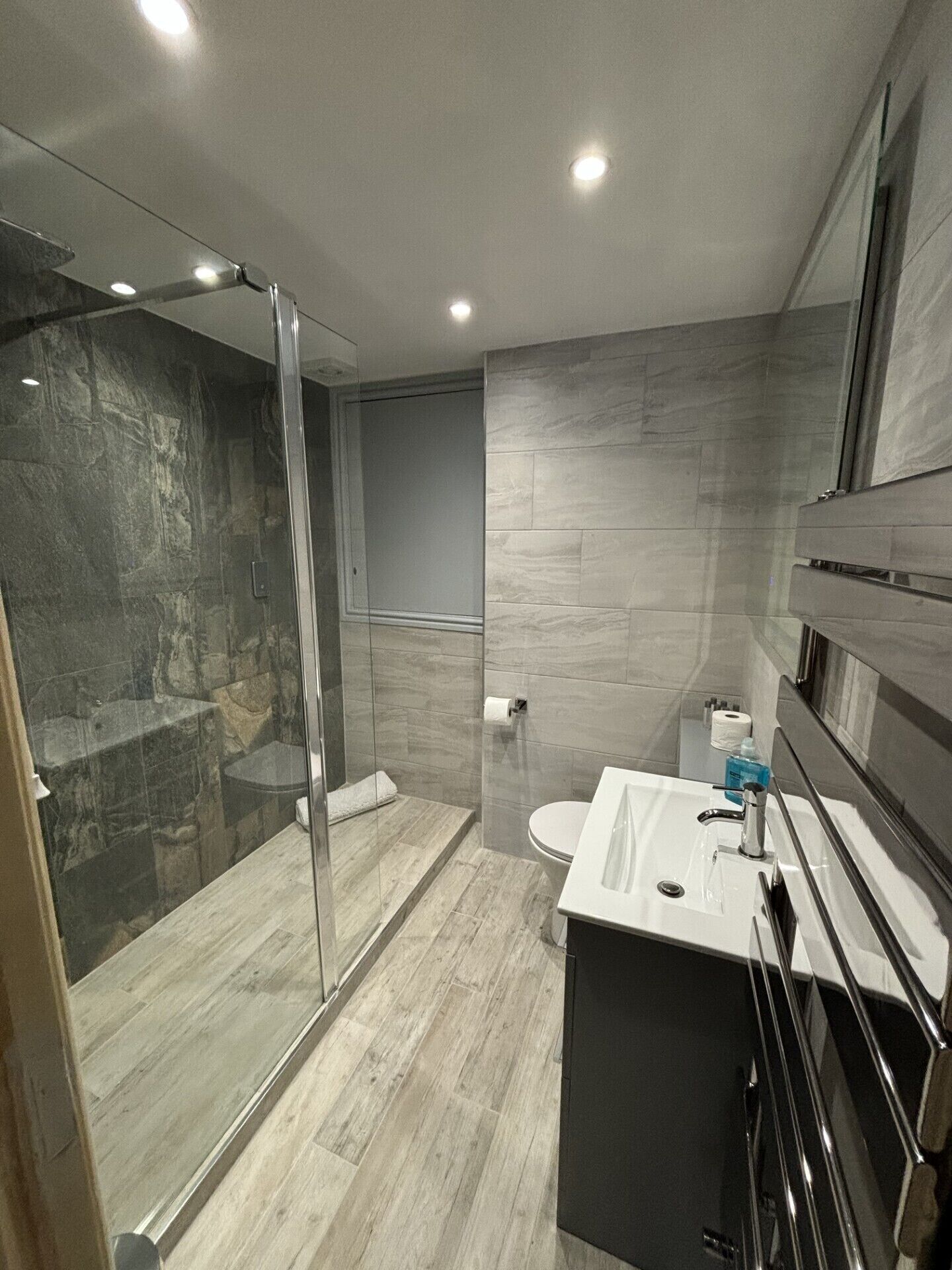 Un baño moderno con ducha de vidrio, inodoro y lavamanos con espejo.
