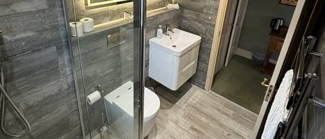 A modern bathroom with a glass-enclosed shower, a white sink, and a large mirror.