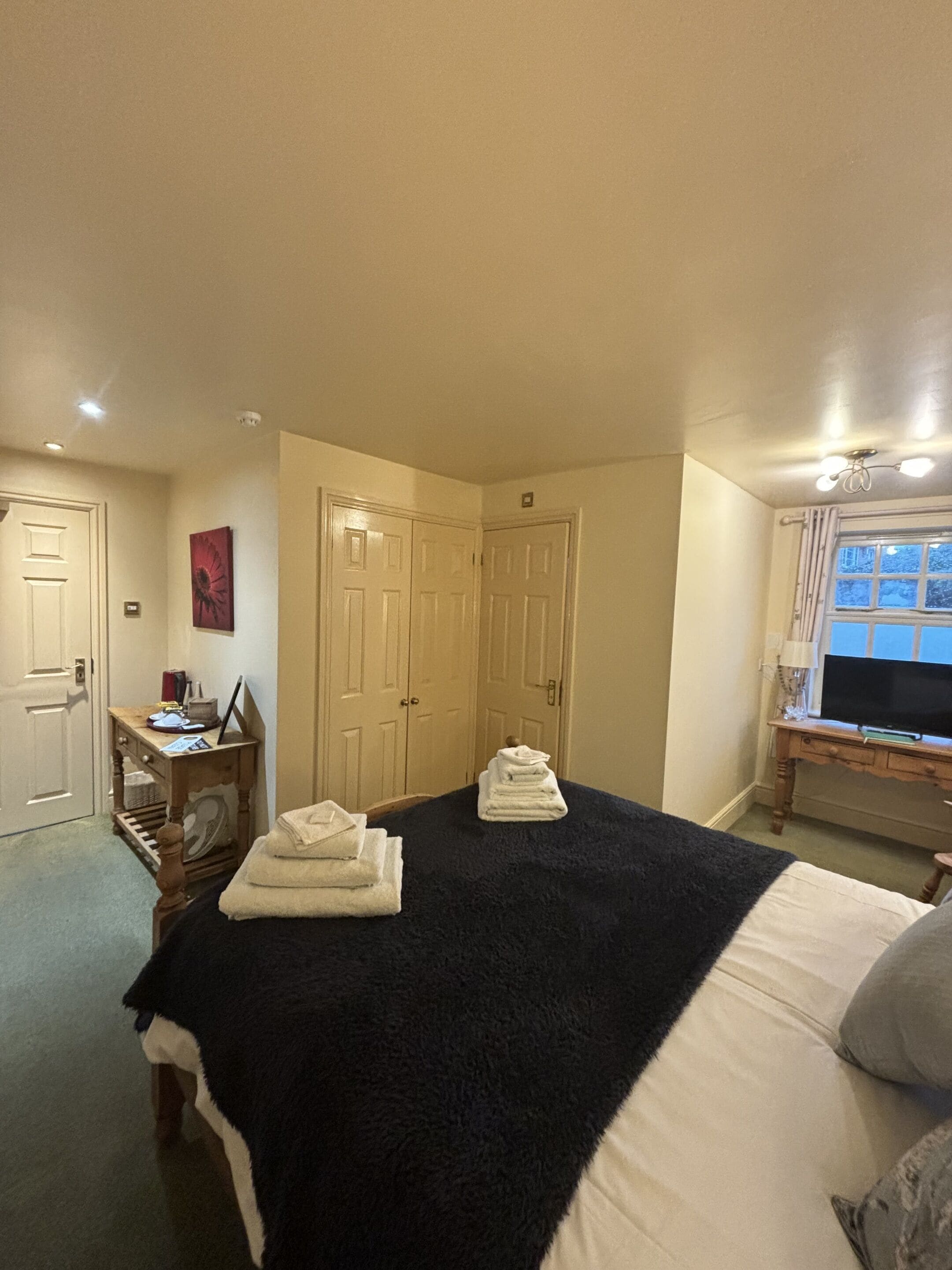 A bedroom with a bed, a desk, a chair, and a TV.