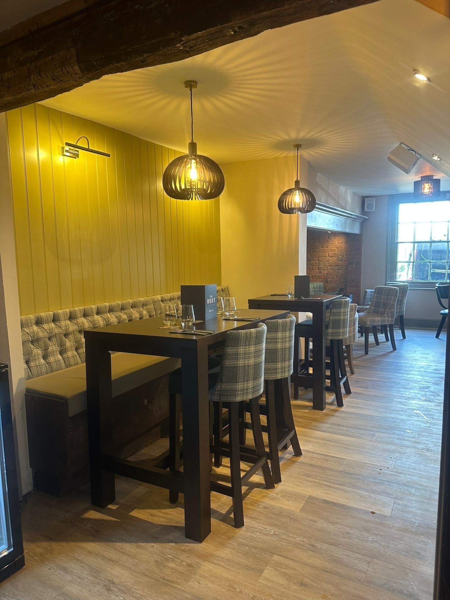 Ein Restaurant mit Holzboden, hoher Decke und einer Sitzgruppe bestehend aus einer Bank und Stühlen.