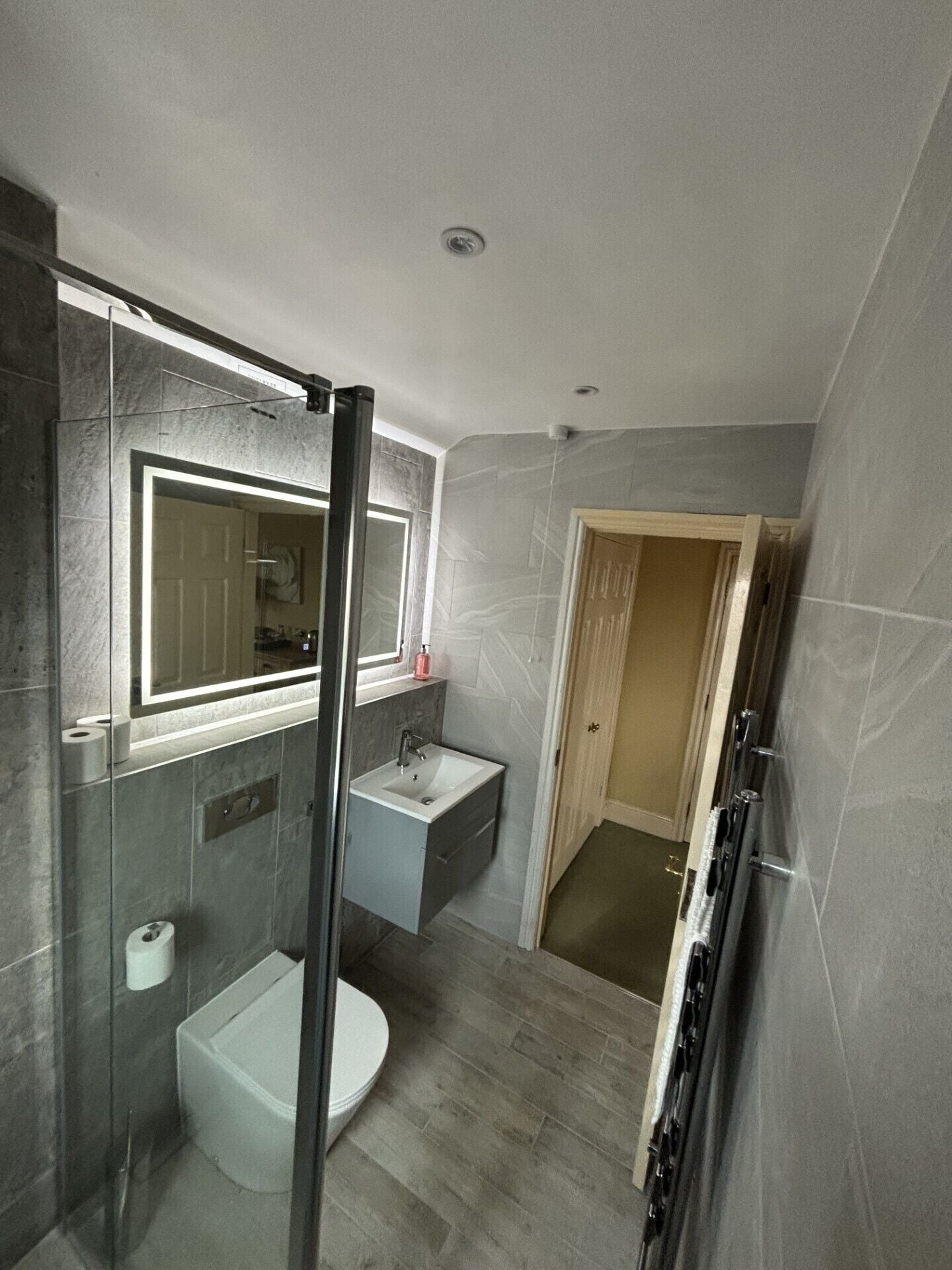 A modern bathroom with a glass shower enclosure, a white sink, and a toilet.