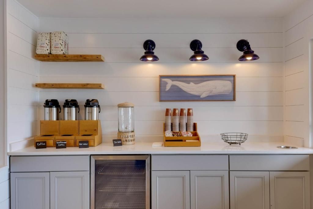 A kitchen with white cabinets, a coffee station, and a whale painting on the wall.