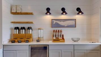 A kitchen with white cabinets, a coffee station, and a whale painting on the wall.