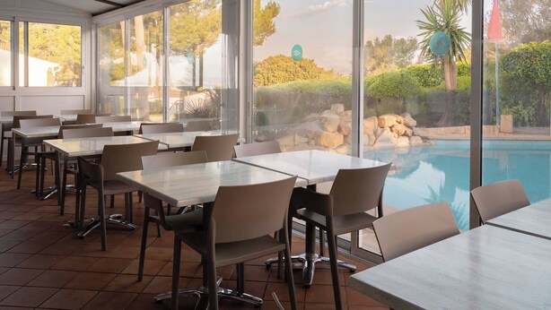 A restaurant with outdoor seating overlooking a pool and garden. - Ona Aucanada Club (Alcúdia)