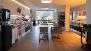 A modern kitchen with a dining area, equipped with appliances, a coffee machine, and a view of the outdoors. - Ona Aucanada Club (Alcúdia)