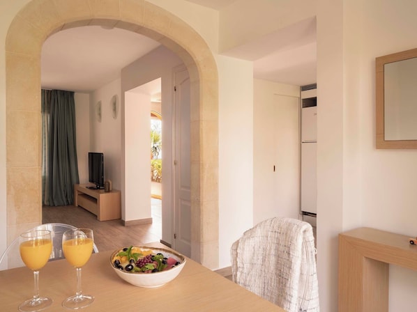 A modern room with a dining table, two glasses of orange juice, a bowl of fruit, a television, and a mirror on the wall. - Ona Aucanada Club (Alcúdia)