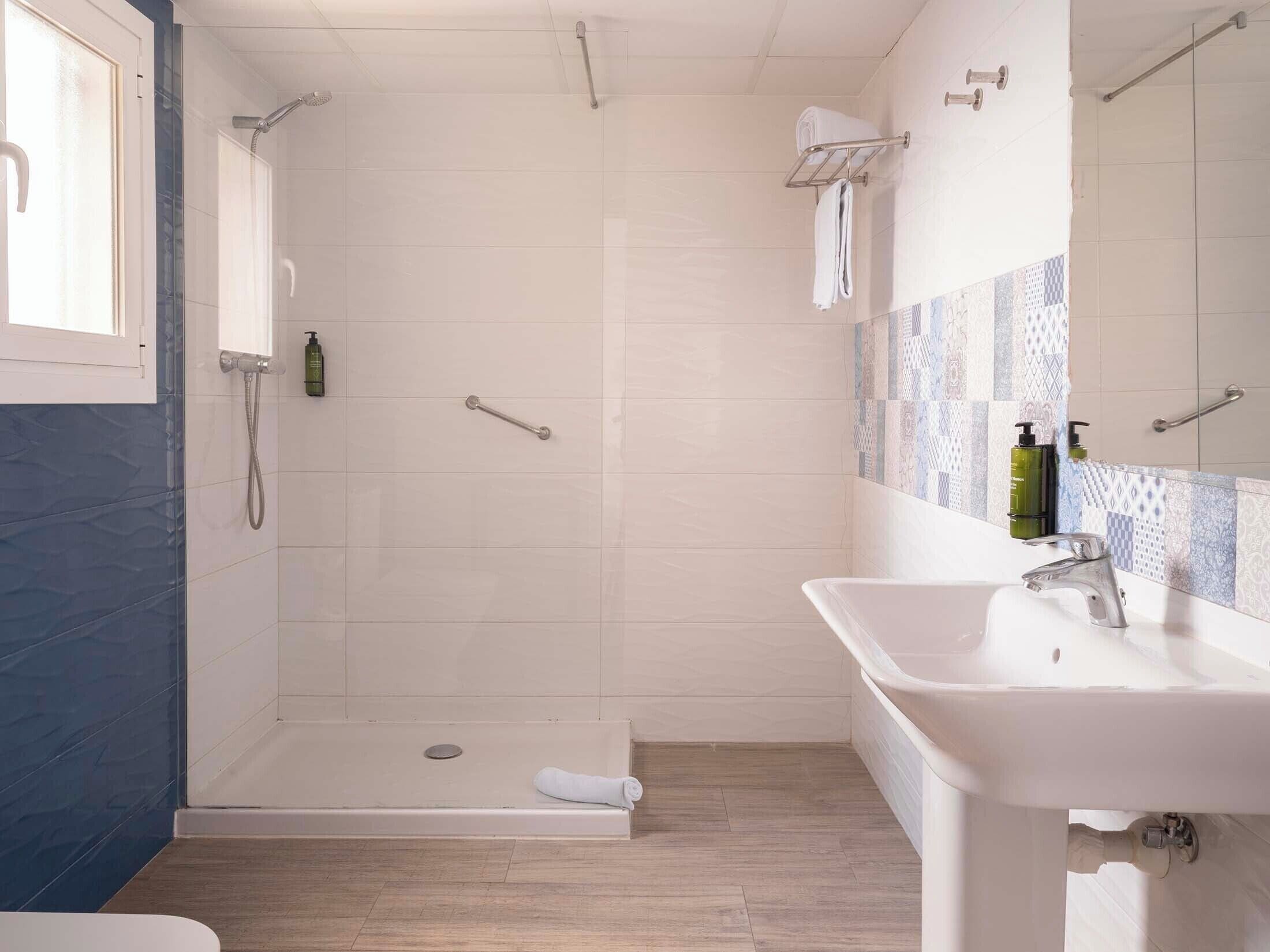 A modern bathroom with a walk-in shower, a sink, and a mirror.