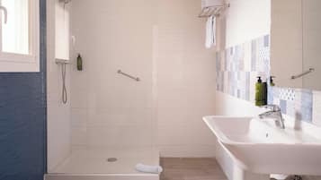 A modern bathroom with a walk-in shower, a sink, and a mirror.