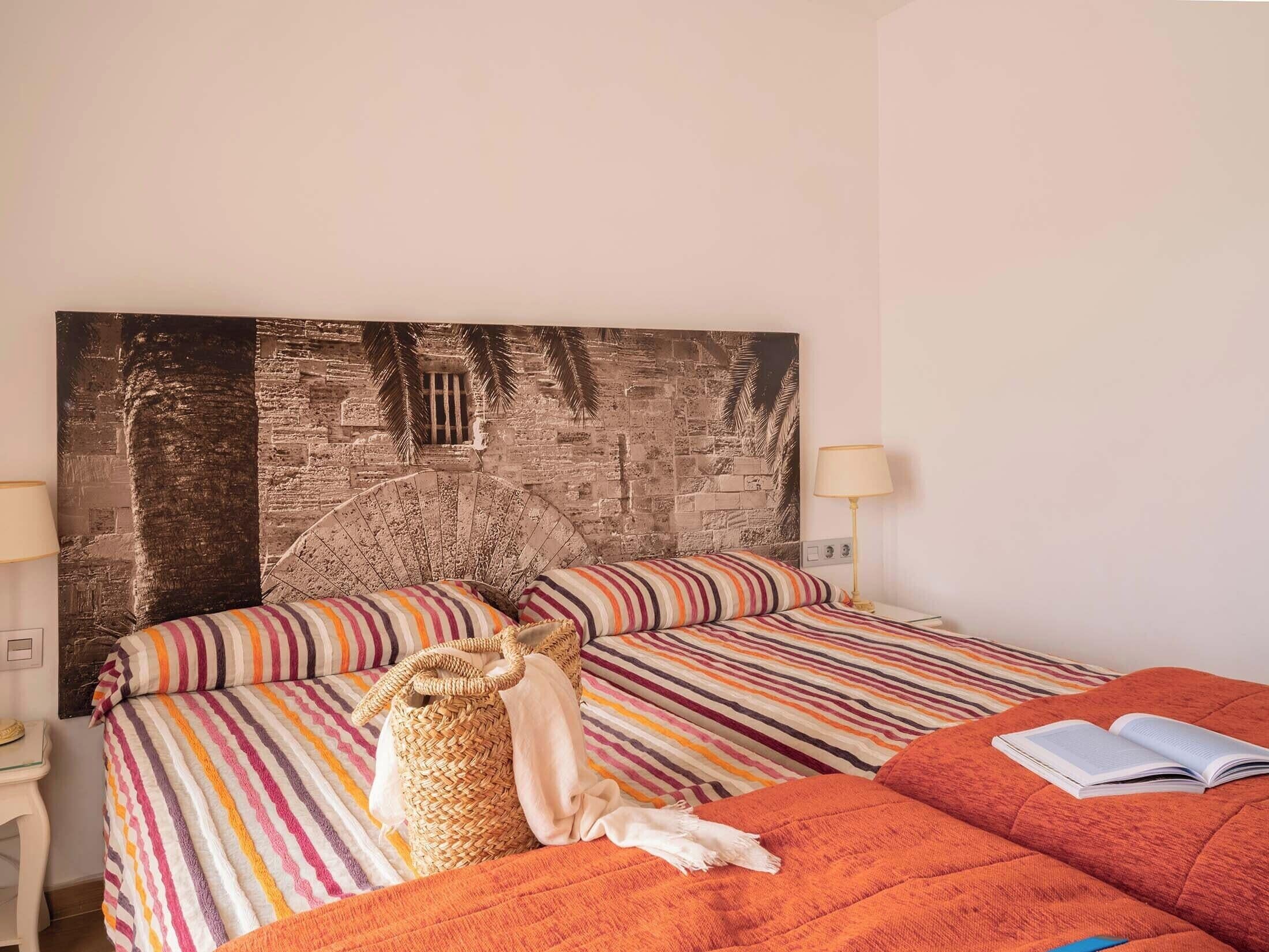 A bedroom with a bed, a reading lamp, and a large wall art piece.