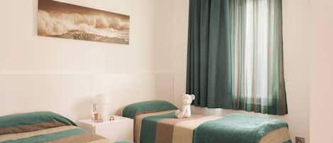 Une chambre d’hôtel avec deux lits, une table de chevet, une lampe, un ours en peluche et un tableau au mur.