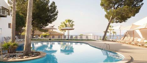 A swimming pool with lounge chairs and palm trees.