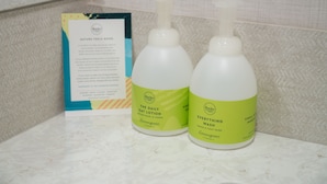 Two bottles of lotion and a pamphlet on a bathroom counter.