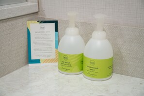 Two bottles of lotion and a pamphlet on a bathroom counter. - The Dorothy Motel (Banff)