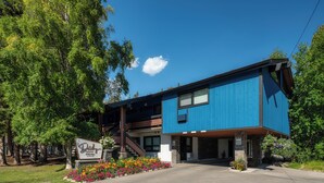 A two-story building with a blue exterior, a signboard, and a flower bed in front.
